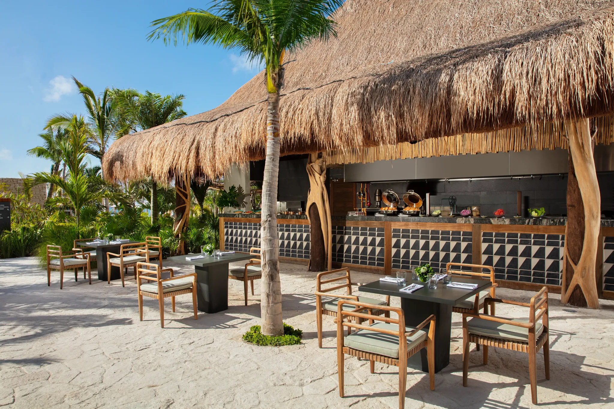 Barefoot Grill at Impression Moxché by Secrets featuring a thatched palapa, outdoor seating, and casual open-air lunch setting.