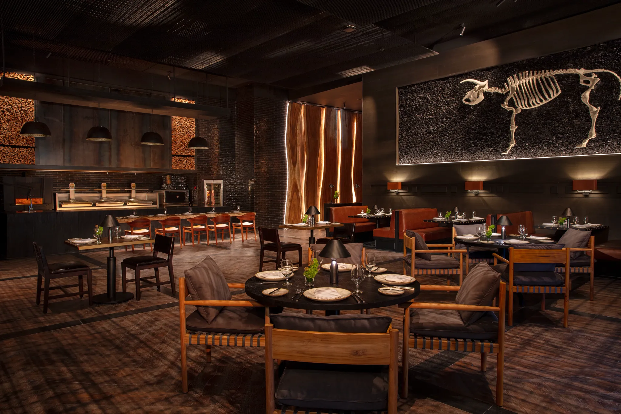 Ember steakhouse at Impression Moxché by Secrets featuring a moody fire-grill dining room, open kitchen, and upscale steakhouse ambiance.