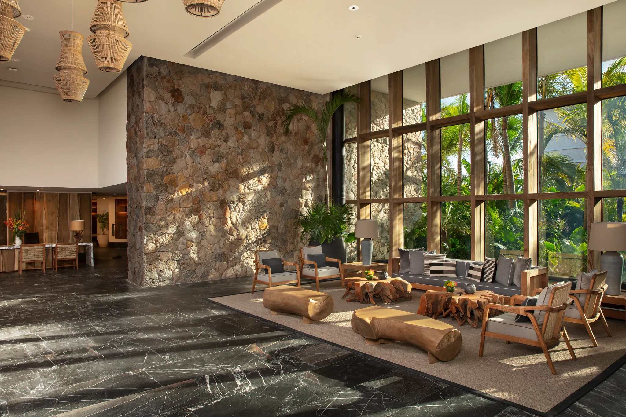 Modern stone-accented lobby with floor-to-ceiling windows at Impression Moxché by Secrets.