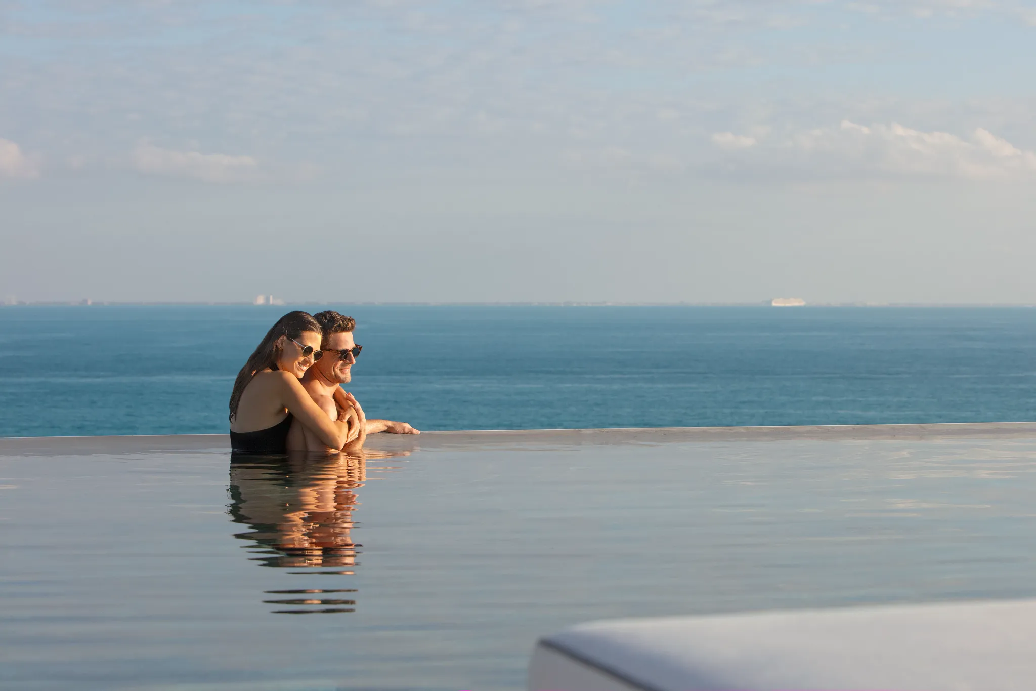 Romantic couple embracing in rooftop infinity pool at sunset at Impression Moxché by Secrets.