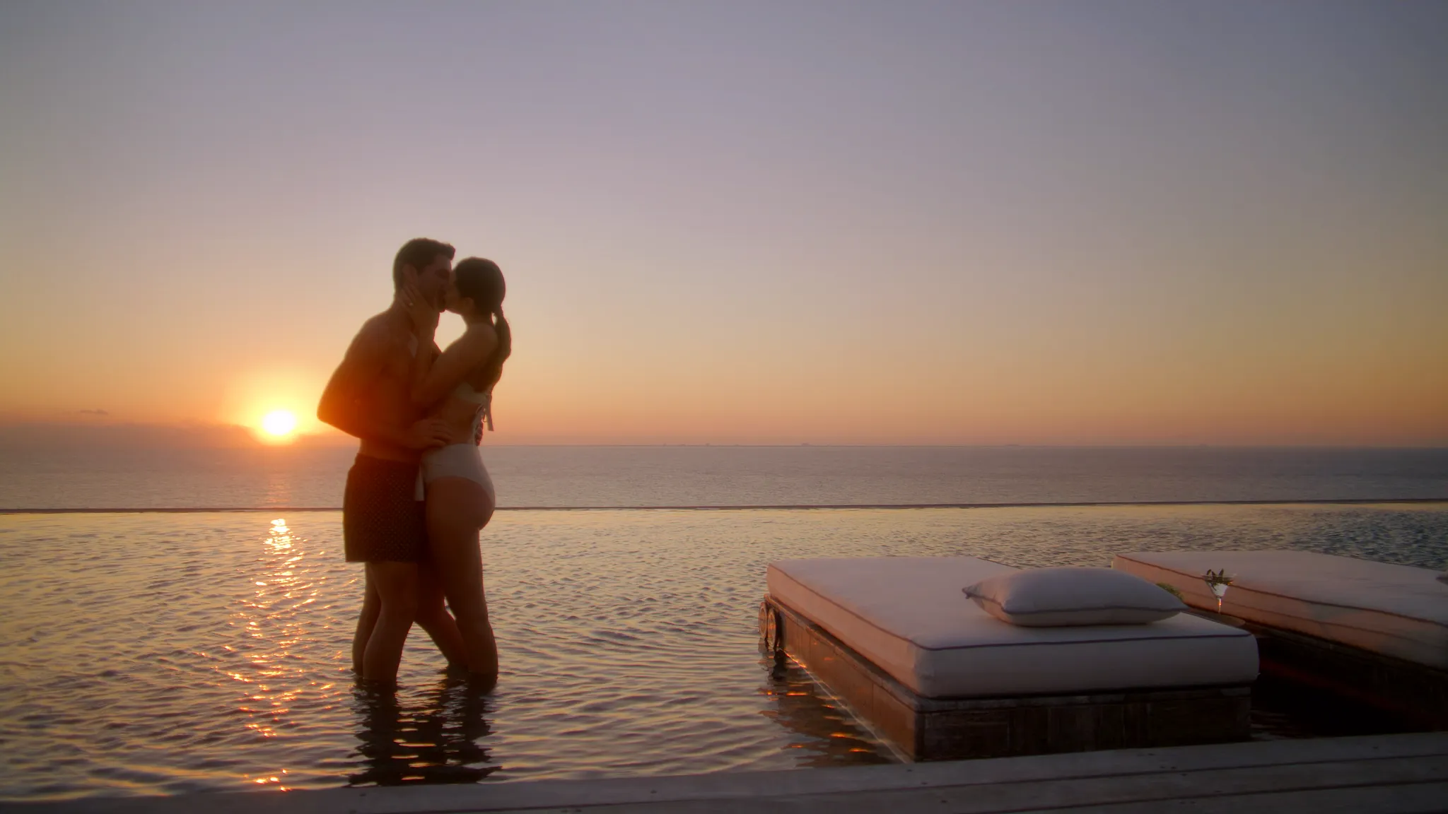 Couple embracing at sunset in the infinity pool at Impression Moxché by Secrets.