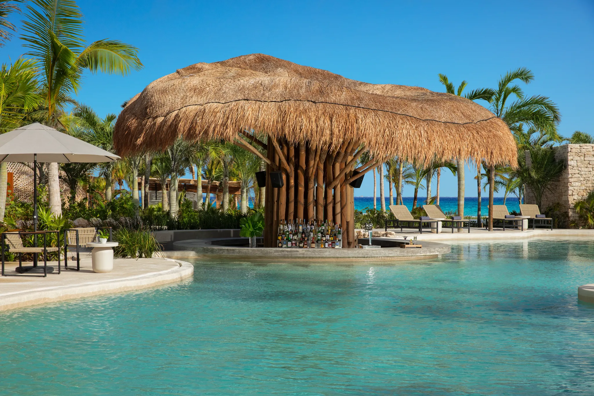 Mantarray swim-up bar at Impression Moxché by Secrets featuring a thatched palapa roof, turquoise pool, and tropical oceanfront setting.